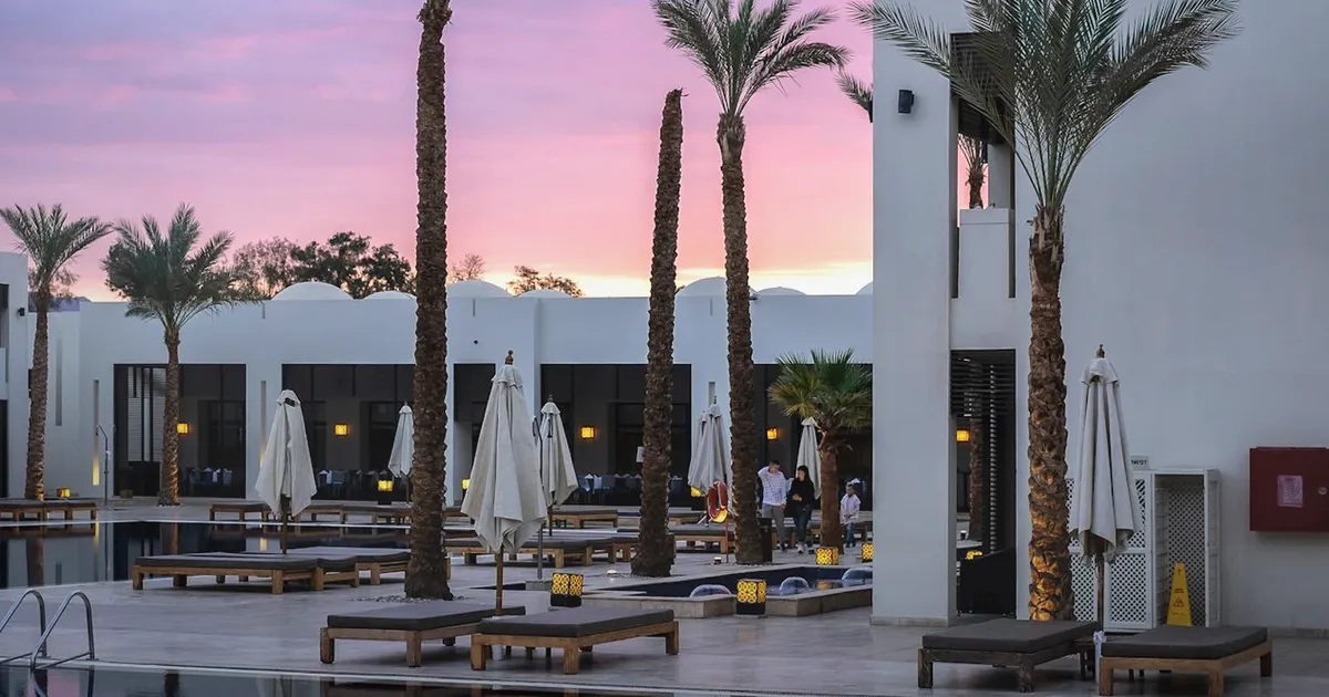 Realistic luxury hospitality interior with pool reflections, palms, and evening light, uniquely composed for Human Made, Hugo Boss, and...
