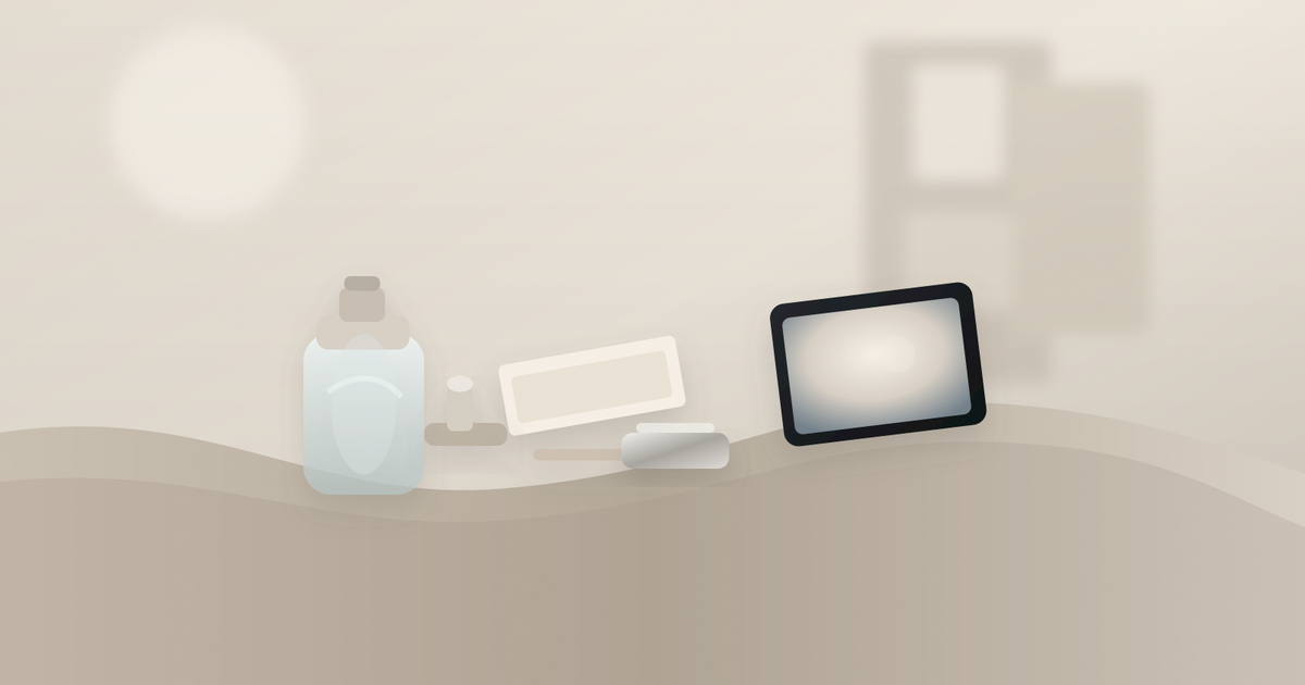 Low-angle dawn view of a travertine medspa counter with one frosted bottle, a tilted tablet, tray, and intake sheets.
